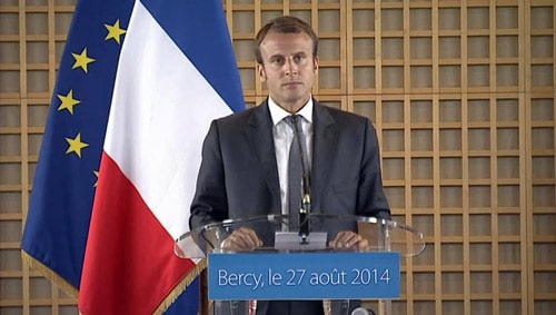 emmanuel macron color standing podium speaking flag background via servetolead.com