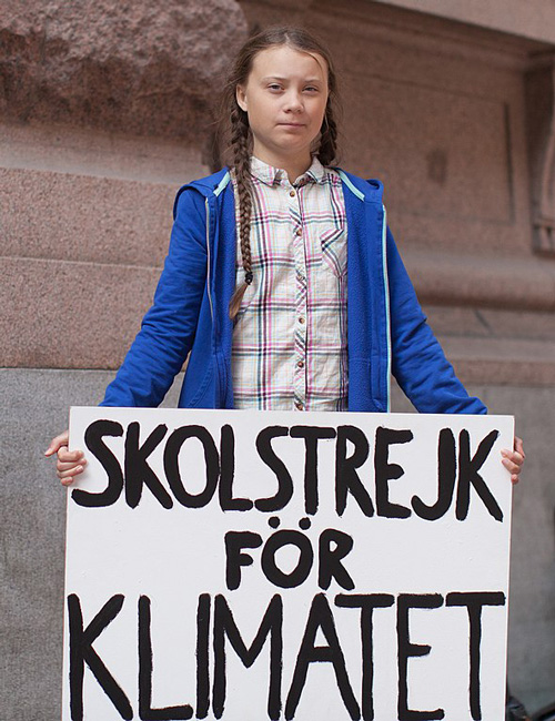 greta thunberg color standing blue jacket holding climate protest placard via @servetolead.com