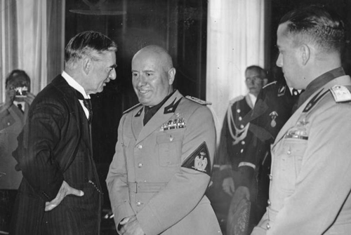 neville_chamberlain_benito_mussolini_ciano_talking_informal_munich_1938_black_and_white_via servetolead.com