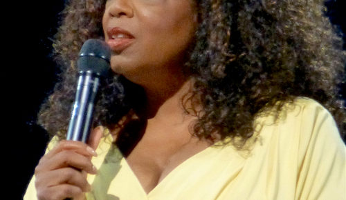 oprah winfrey speaking into microphone in yellow dress