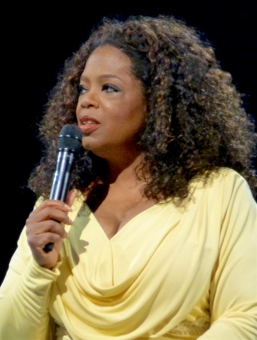 oprah winfrey speaking into microphone in yellow dress