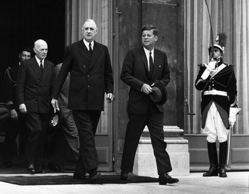 John F. Kennedy and Charles De Gaulle walking together black and white photo holding hats elysee palace via @via servetolead.com