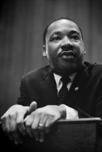 Martin Luther King Jr speaking at podium hands in front black and white via @servetolead.com